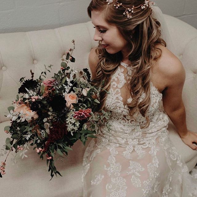 J & B Bridals bride sitting on vintage couch with bouquet